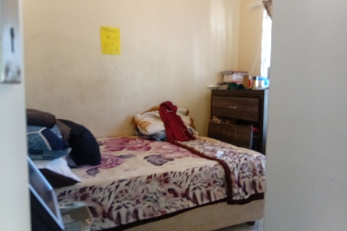 A bedroom interior featuring tiled flooring and standard wall finishes, currently showing signs of wear and requiring cosmetic updates.