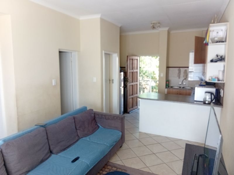 Open plan living area featuring tiled flooring and a functional kitchen with a breakfast bar, leading to an exterior door.