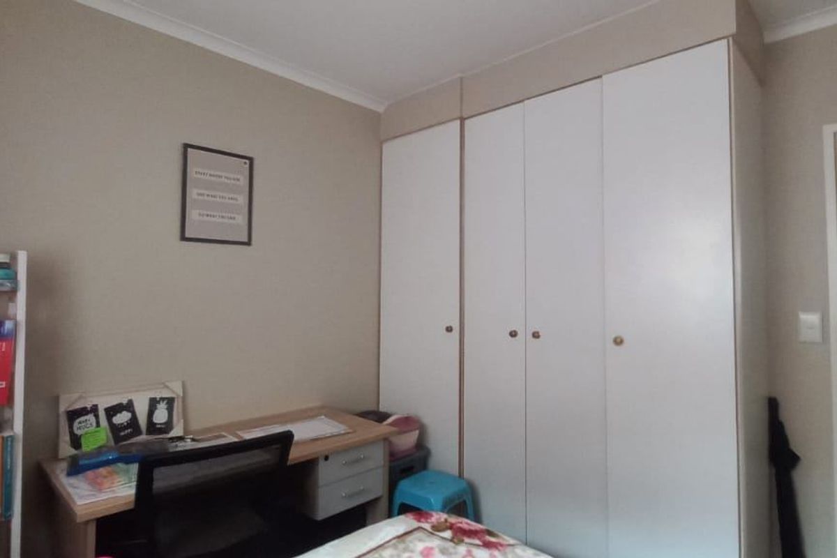 A bedroom featuring a built-in wardrobe and a doorway leading to an adjacent room.