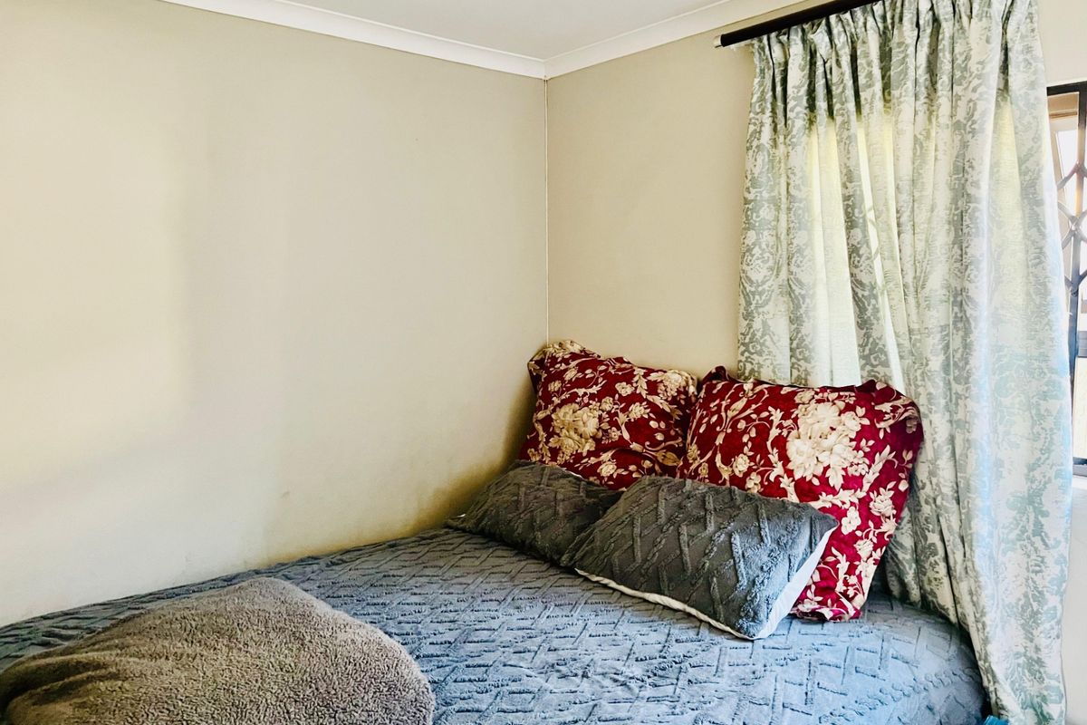 A compact bedroom featuring neutral wall finishes and a window with installed curtain rod.