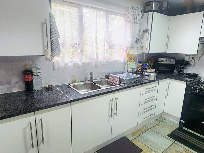 A functional kitchen featuring granite countertops, a double basin sink, built-in oven with gas hob, and ample upper and lower cabinetry.