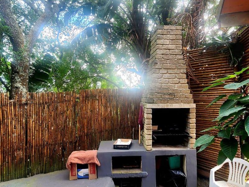 Outdoor patio area featuring a built-in brick braai, concrete base, and natural bamboo privacy fencing, ideal for outdoor entertaining.