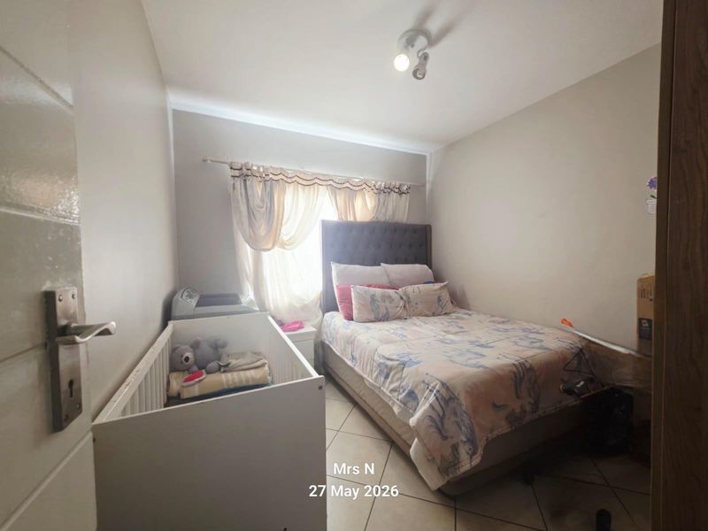 A functional bedroom featuring tiled flooring and neutral wall finishes, providing a comfortable space for rest.
