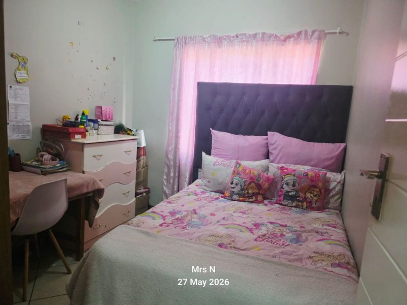 A bedroom featuring tiled flooring and a curtain rod, currently utilized as a child's bedroom.