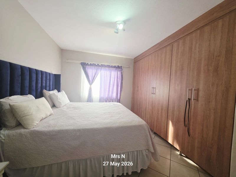 A bedroom featuring built-in wooden cupboards and tiled flooring, providing functional storage space.