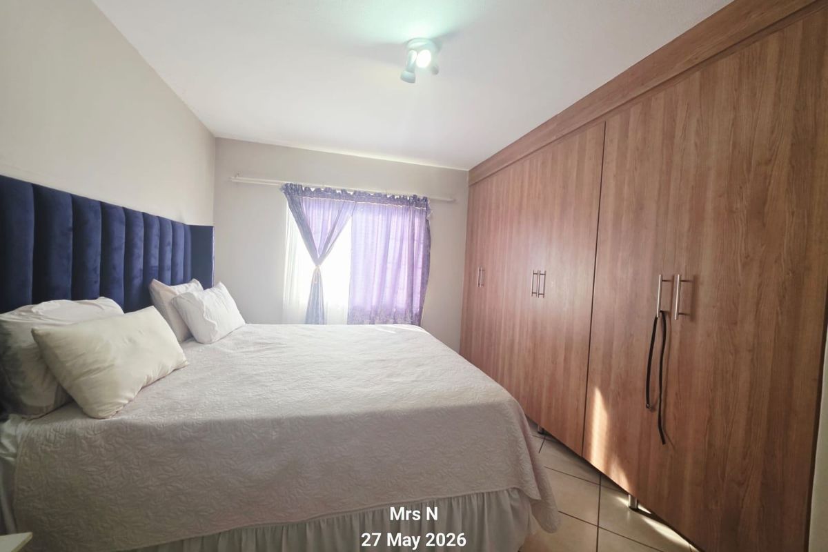 A bedroom featuring built-in wooden cupboards and tiled flooring, providing functional storage space.