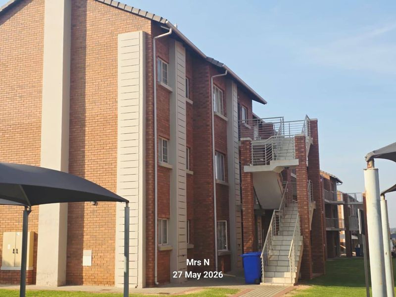 Exterior view of a multi-story apartment building featuring face brick construction, external staircases with metal railings, and paved ground-level walkways.