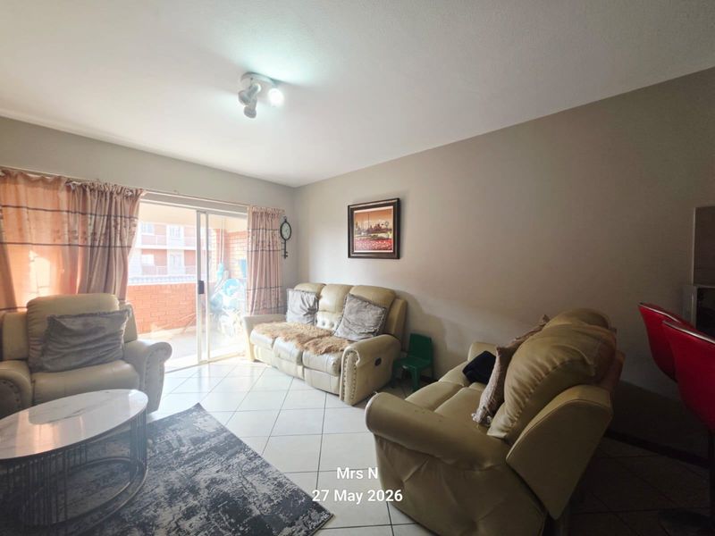 A living room featuring tiled flooring and a sliding glass door providing access to an outdoor balcony area.