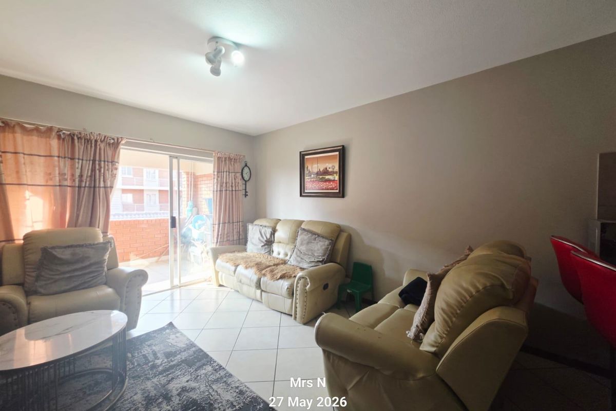 A living room featuring tiled flooring and a sliding glass door providing access to an outdoor balcony area.