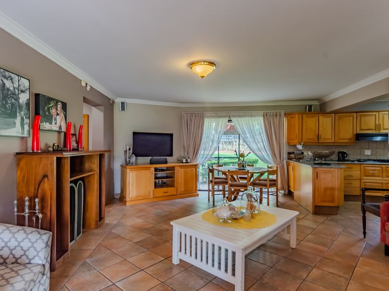Open-plan living and kitchen area featuring tiled flooring, wooden cabinetry, and sliding glass doors providing access to the outdoor space.