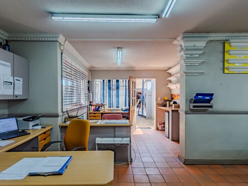 Functional office space featuring tiled flooring, built-in cabinetry, and decorative crown molding, with direct access to an exterior area.