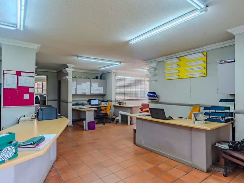 A functional office space featuring terracotta tile flooring, built-in cabinetry, and decorative ceiling cornices, providing a practical layout for a professional work environment.