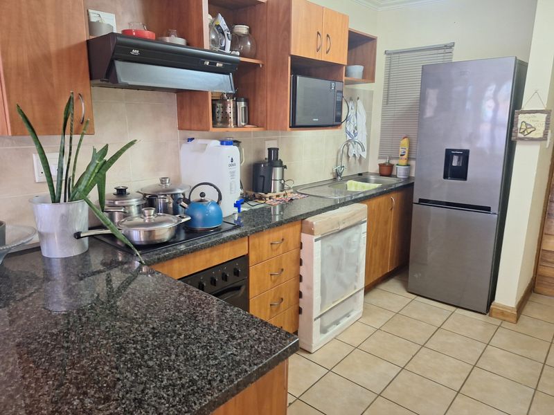 A functional kitchen featuring granite countertops, wooden cabinetry, a built-in oven with extractor fan, and tiled flooring.
