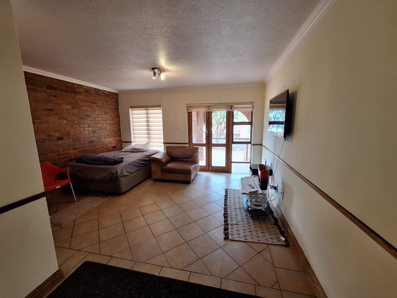 A bedroom featuring an exposed brick wall, ceramic tiled flooring, and glass panelled doors leading to an outdoor area.