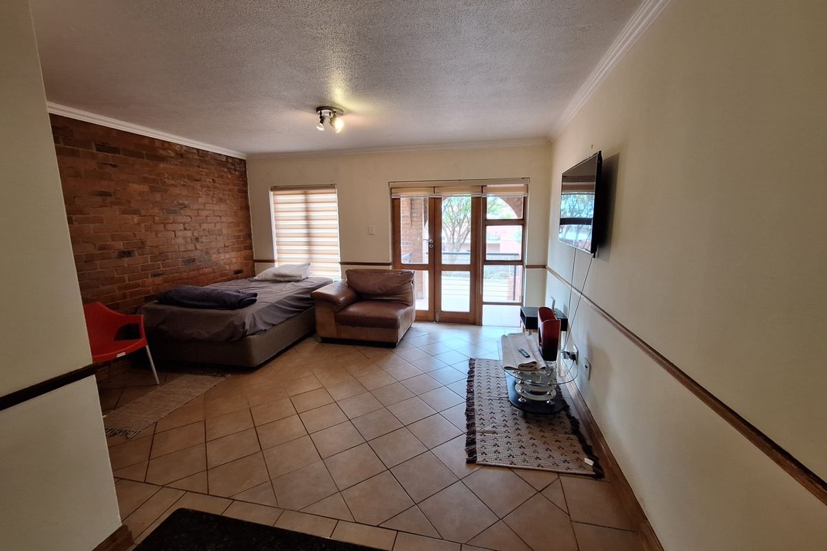 A bedroom featuring an exposed brick wall, ceramic tiled flooring, and glass panelled doors leading to an outdoor area.