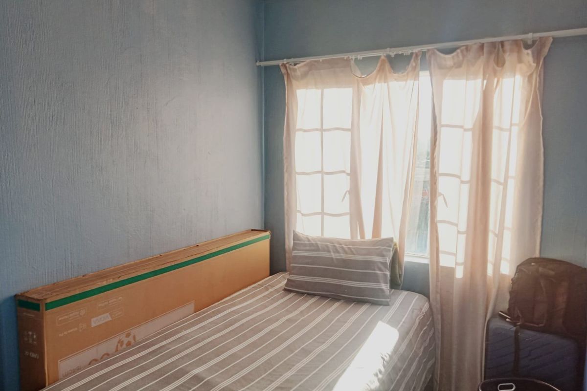 A bedroom featuring a window with a curtain rod, providing natural light to the space.