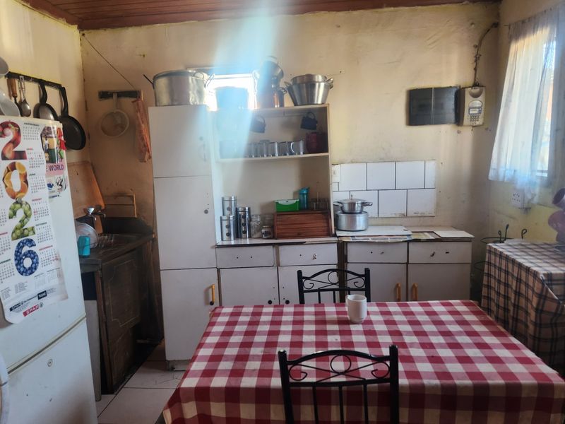 A dated kitchen featuring original built-in cabinetry, tiled splashback, and timber ceiling, offering significant potential for modernization and renovation.