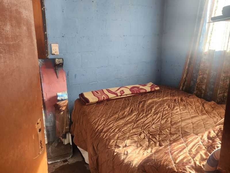 A compact bedroom featuring exposed blockwork walls and a timber ceiling, requiring cosmetic updates to improve the overall finish and aesthetic appeal.