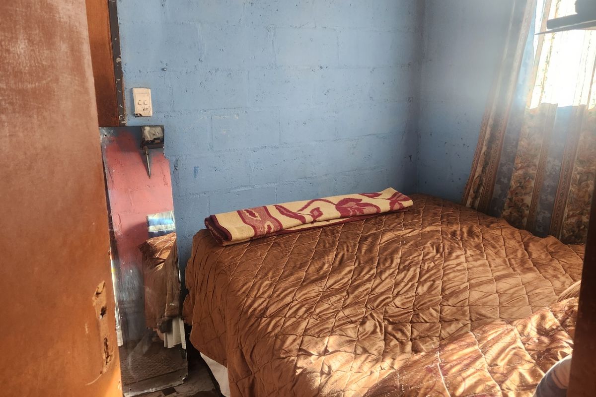 A compact bedroom featuring exposed blockwork walls and a timber ceiling, requiring cosmetic updates to improve the overall finish and aesthetic appeal.
