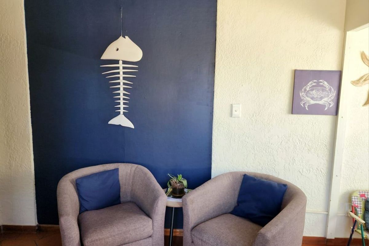 A cozy seating area featuring a dark blue accent wall, textured cream walls, and terracotta floor tiles.