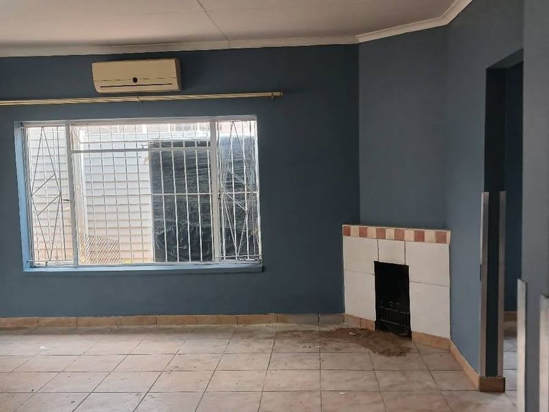 An empty living room featuring tiled flooring, a built-in fireplace, and a wall-mounted air conditioning unit.