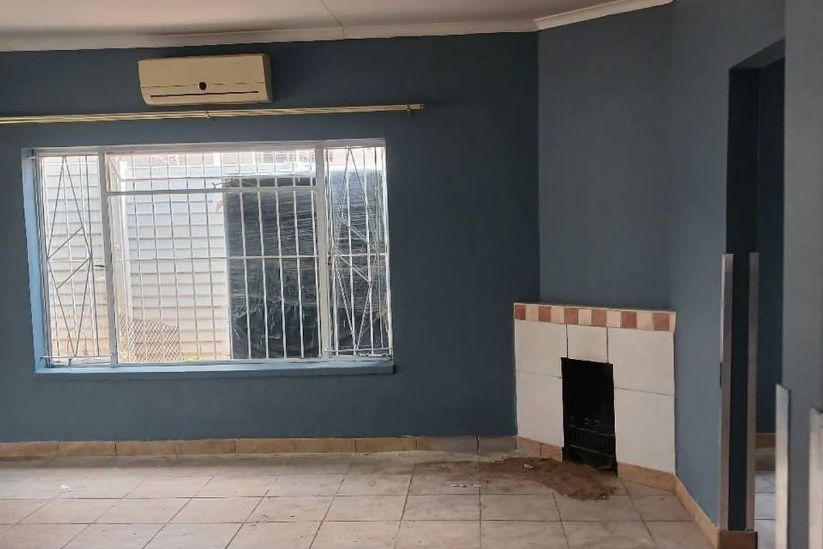 An empty living room featuring tiled flooring, a built-in fireplace, and a wall-mounted air conditioning unit.