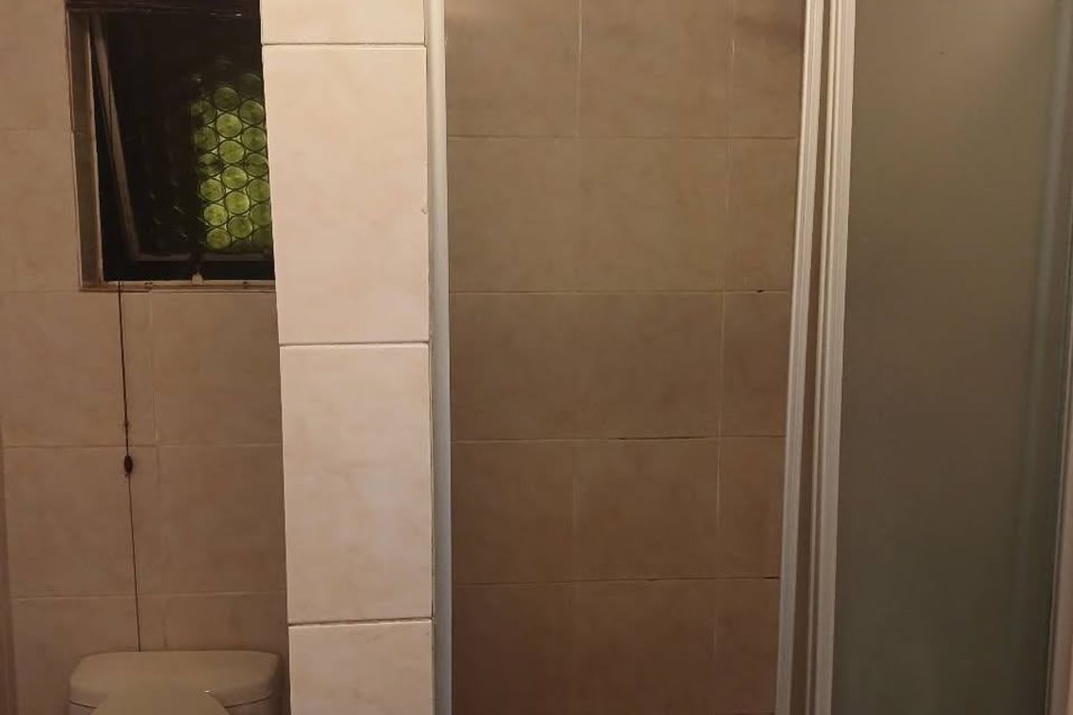 A functional bathroom featuring a shower enclosure, toilet, and tiled wall finishes. The space is ready for a modern update.