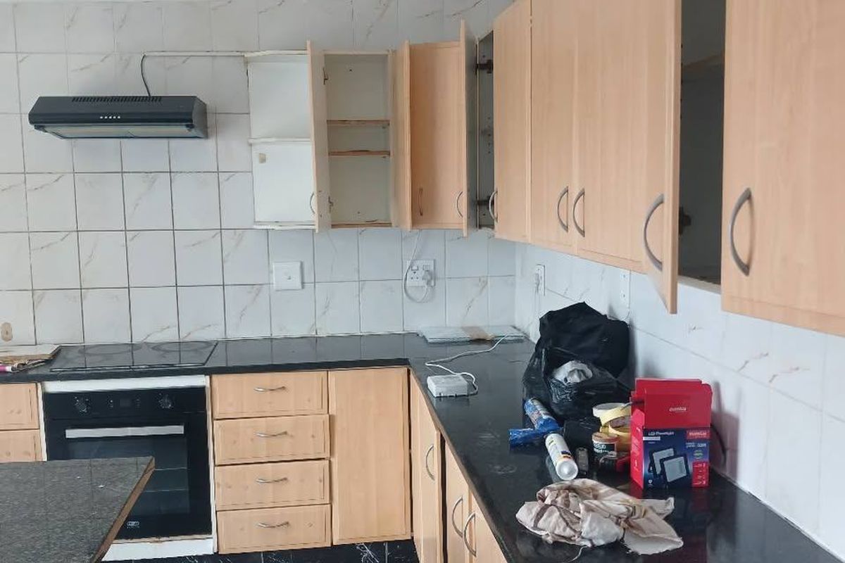 A functional kitchen featuring granite countertops, tiled backsplash, and built-in oven, currently requiring some maintenance and cabinet repairs.