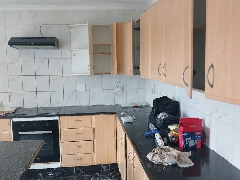 A functional kitchen featuring granite countertops, tiled backsplash, and built-in oven, currently requiring some maintenance and cabinet repairs.