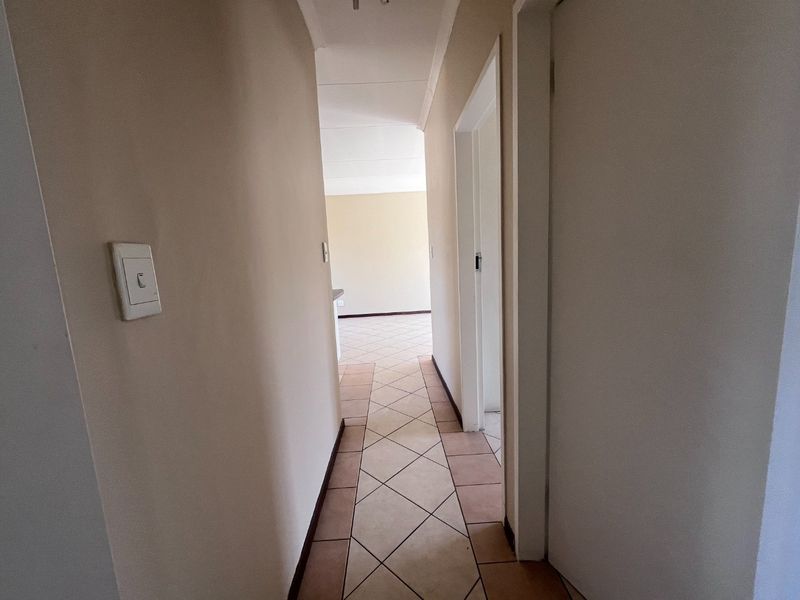 A functional hallway with tiled flooring connecting the living areas, featuring neutral wall tones and standard door frames.