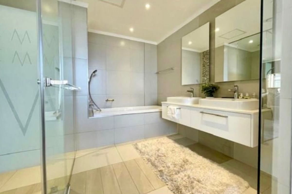 Modern bathroom featuring a floating double vanity, built-in bathtub, and a separate glass-enclosed shower with contemporary tile finishes.