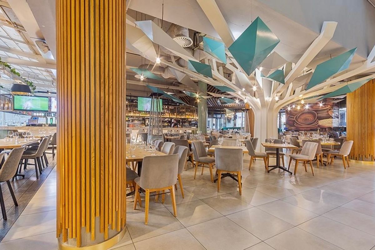 A modern, well-appointed clubhouse or restaurant space featuring unique sculptural ceiling elements, timber-clad columns, and high-quality tiled flooring throughout.