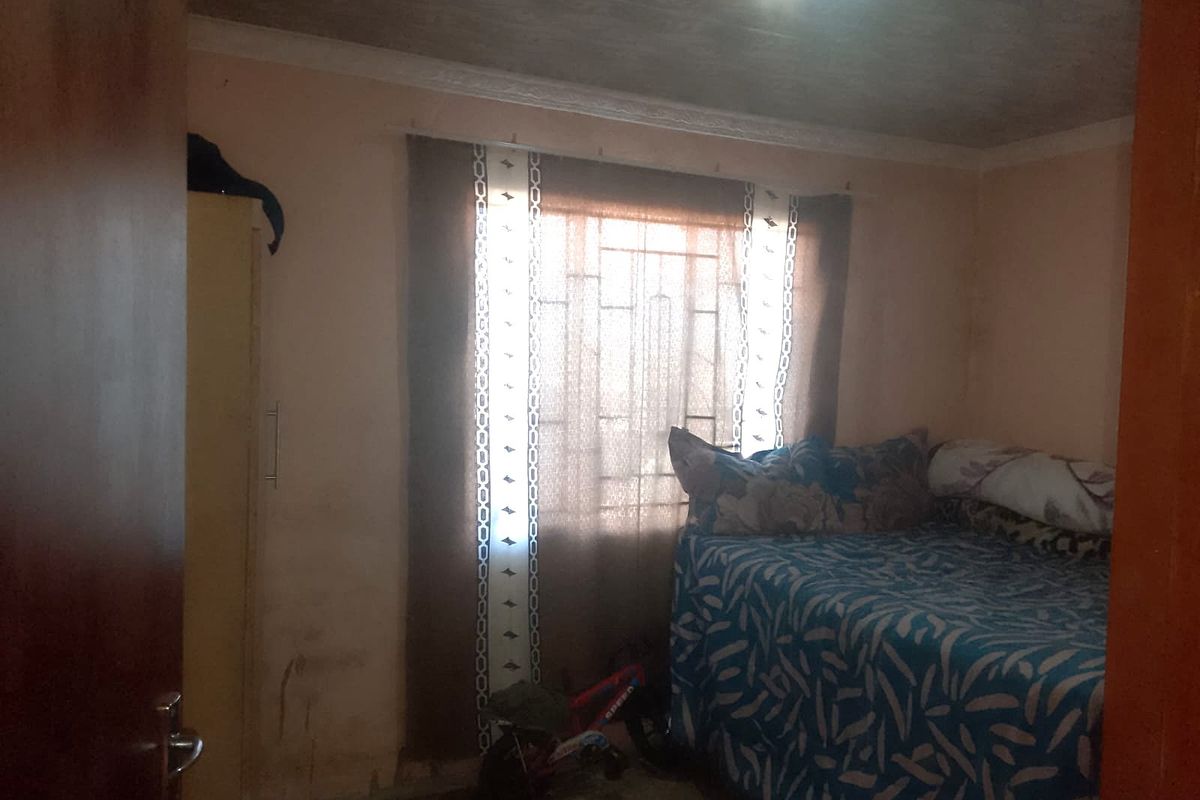 A bedroom featuring security bars on the window, coving, and recessed ceiling lighting, showing signs of wall wear and paint deterioration.