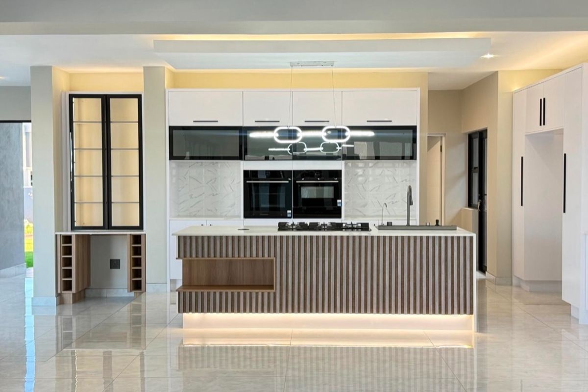 Modern, high-end kitchen featuring a central island with integrated gas hob, built-in appliances, sleek cabinetry, and polished tiled flooring.