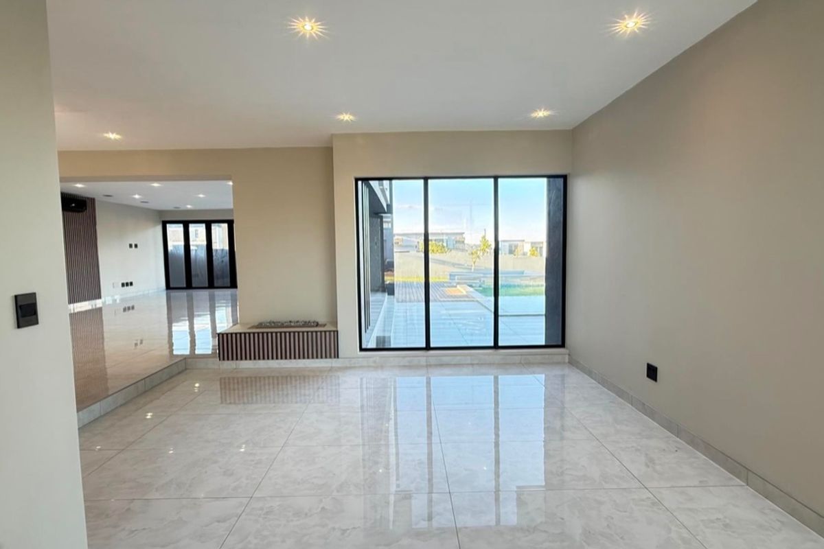 Spacious, modern living area featuring large format porcelain tiles, recessed lighting, and a built-in fireplace with views to the outdoor area.