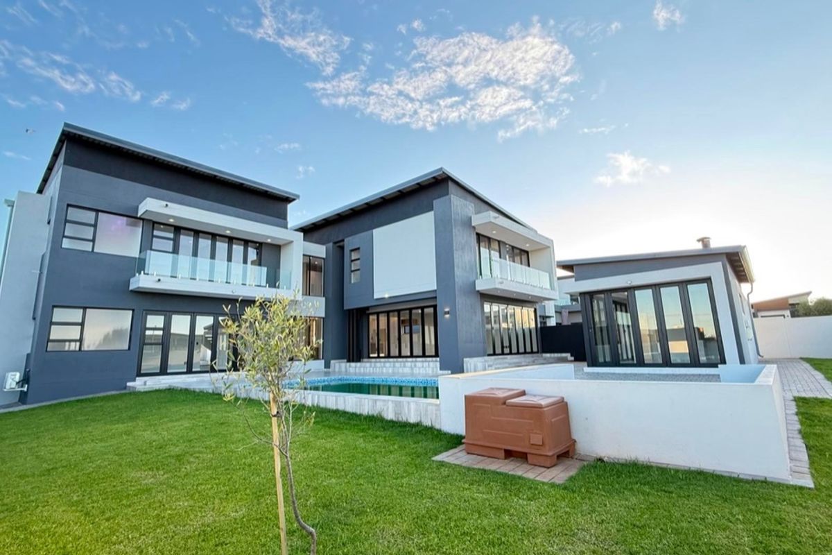 Modern double-story residence featuring a rear garden, swimming pool, and expansive glass sliding doors leading to outdoor living spaces.