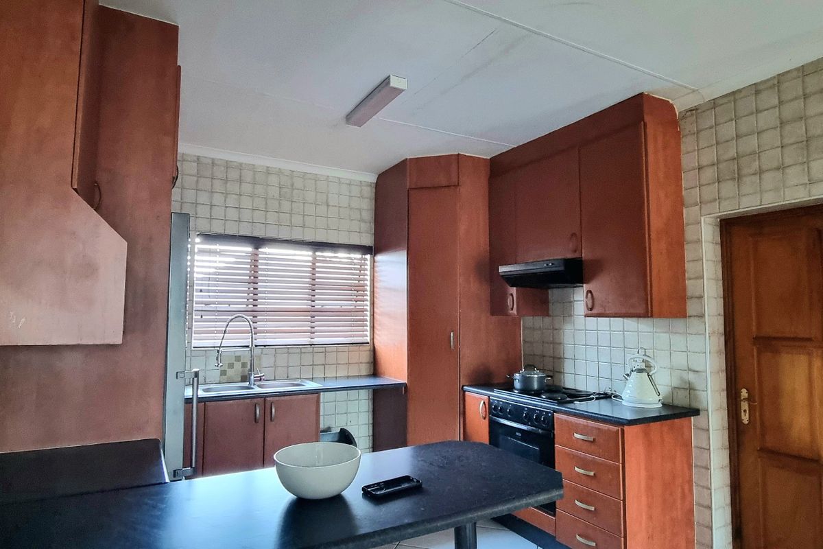 A dated kitchen featuring wooden cabinetry, tiled backsplash, and a functional layout with a breakfast bar and integrated stove area.