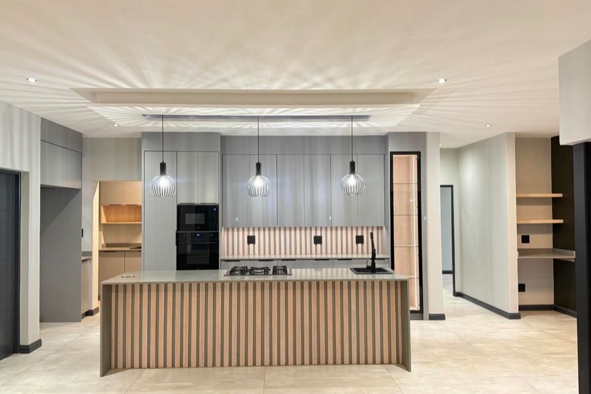 Modern, high-end kitchen featuring a central island with slatted wood detailing, integrated appliances, sleek grey cabinetry, and sophisticated recessed ceiling lighting.