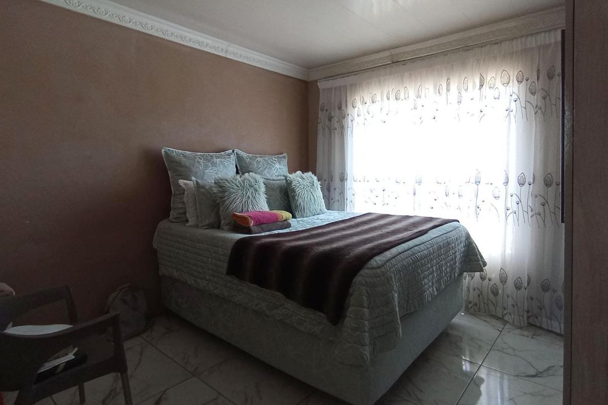 A bedroom featuring tiled flooring and decorative ceiling cornicing, providing a neutral base for interior design updates.