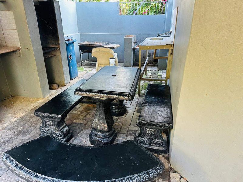 Outdoor patio area featuring a built-in braai, sink, and paved flooring, offering a functional space for outdoor cooking and entertainment.