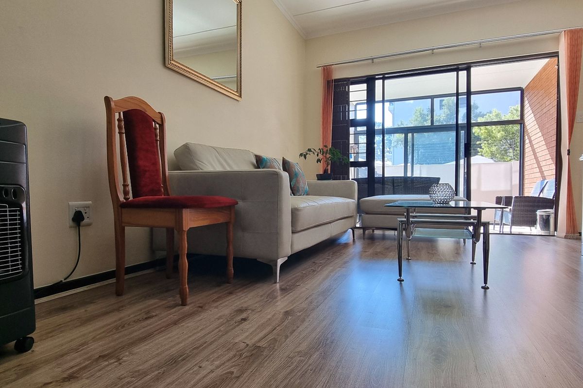 A bright living room featuring modern laminate flooring and large sliding glass doors that provide access to an outdoor patio area.