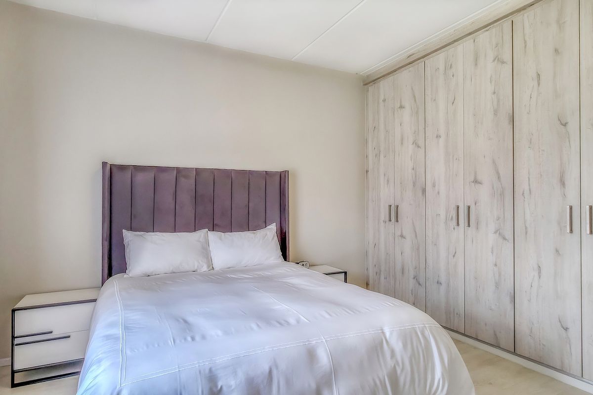 A well-maintained bedroom featuring neutral walls, tiled flooring, and extensive built-in cupboards providing ample storage space.