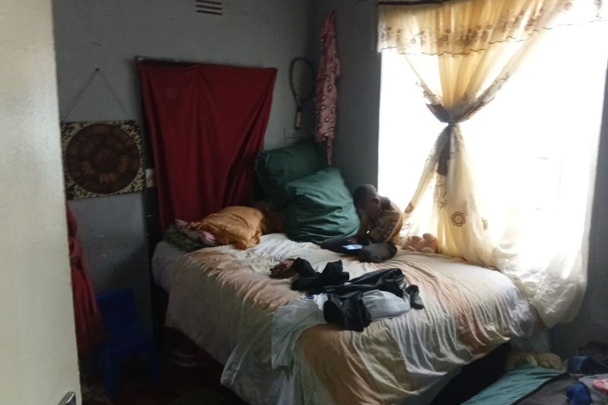A compact bedroom featuring a window with curtains and basic wall finishes, suitable for renovation to improve the overall aesthetic and functionality.