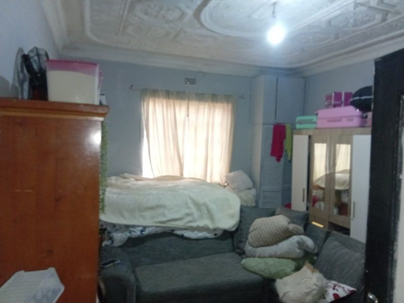 A bedroom featuring ornate ceiling detailing and built-in cupboard storage, offering a functional space with potential for cosmetic updates.