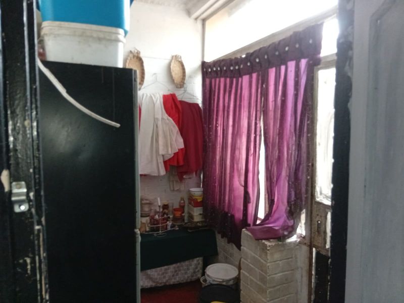 A small utility or storage area featuring exposed brick walls and natural light access, currently used for miscellaneous storage.