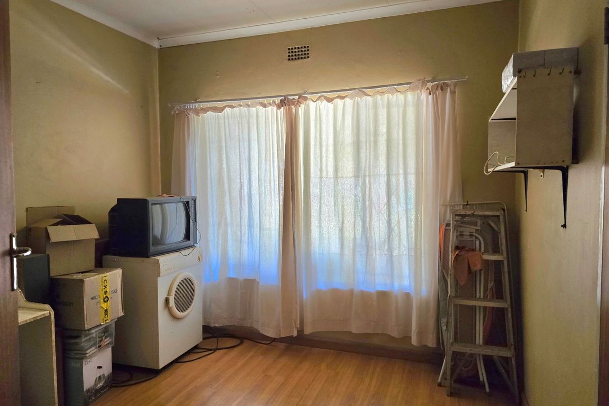 A vacant bedroom featuring laminate flooring and a ventilation grille, offering a blank canvas for renovation and interior design updates.