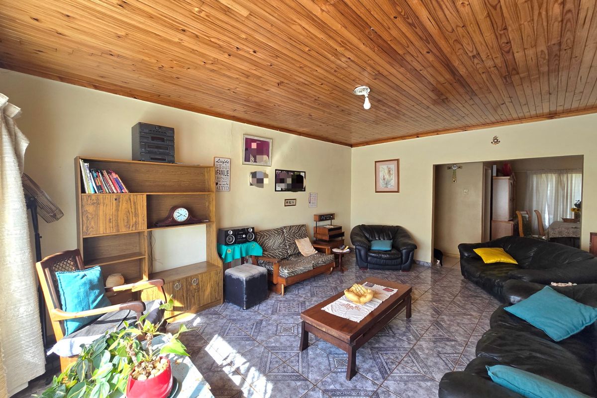 A spacious living room featuring a warm timber tongue and groove ceiling and durable ceramic floor tiles throughout.