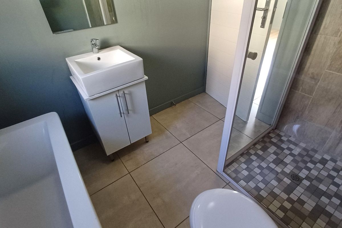 Modern bathroom featuring a vanity with basin, a separate bathtub, and a glass-enclosed shower with mosaic tile accents.