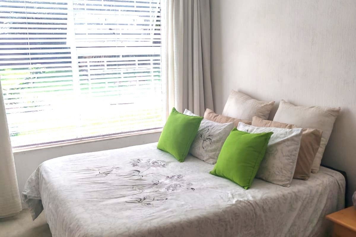 A bedroom featuring a large window with venetian blinds, neutral wall finishes, and carpet flooring, offering a blank canvas for potential updates.