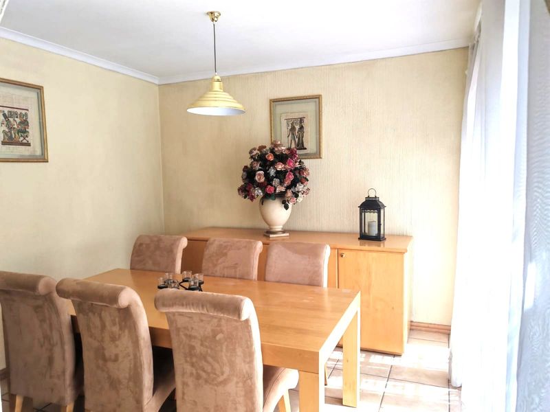 A dining room featuring tiled flooring, coved ceilings, and a central pendant light fixture.